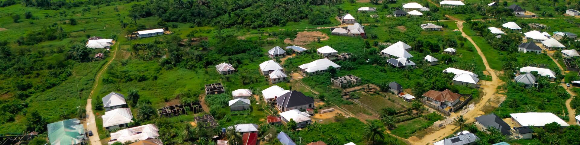 Aerial view of houses nestled amidst lush greenery along the winding river, a vibrant tapestry of earth tones under a vast sky, Yenagoa, Bayelsa Stae, Nigeria.