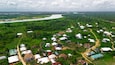 Aerial view of houses nestled amidst lush greenery along the winding river, a vibrant tapestry of earth tones under a vast sky, Yenagoa, Bayelsa Stae, Nigeria.