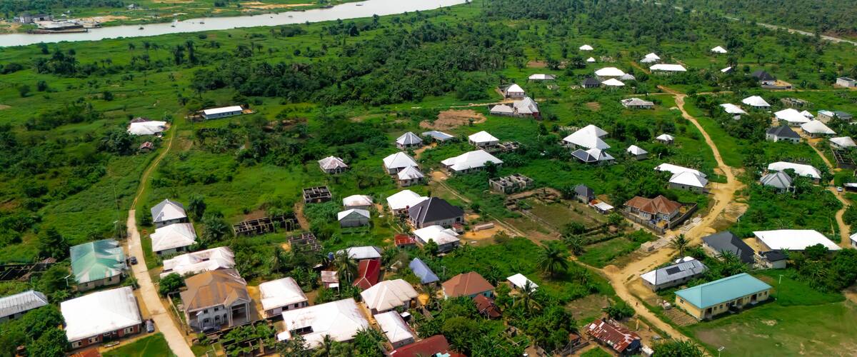 An aerial view of a rural area with scattered houses, a river, and dense greenery.