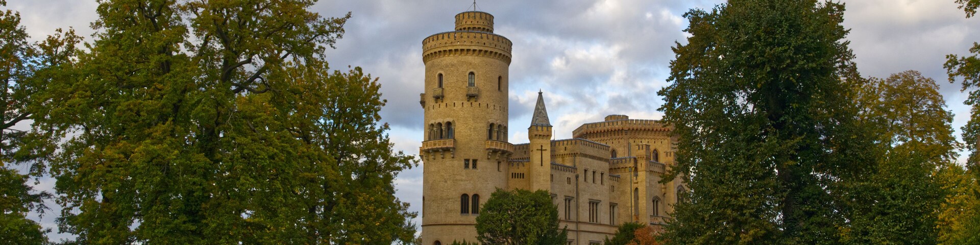 Um castelo rodeado por vegetação exuberante e um céu parcialmente nublado.