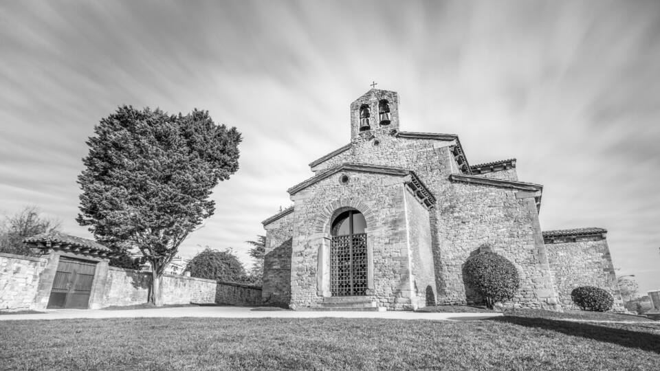 A stone church with a bell tower and arched windows.