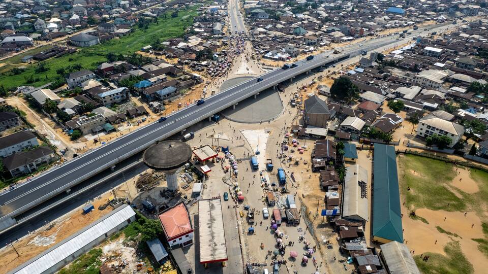An aerial view of a city with a prominent highway, residential areas, and a roundabout.