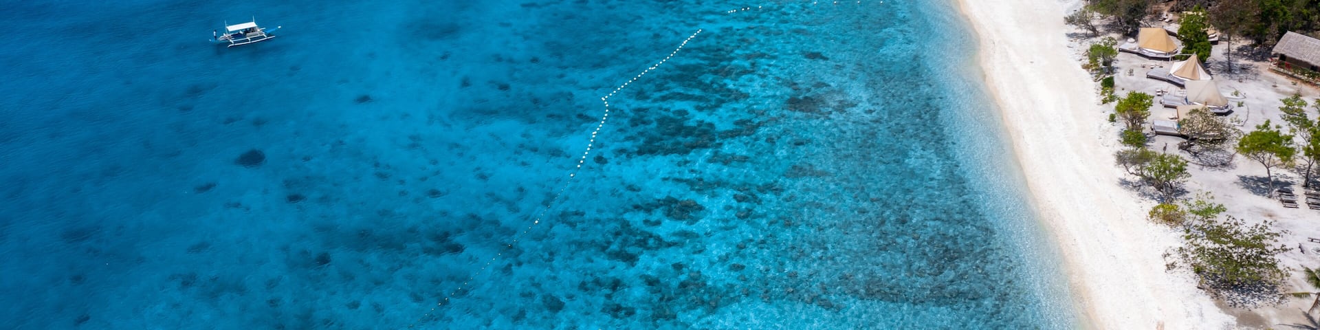 A clear blue sea, a sandy beach, and a boat.