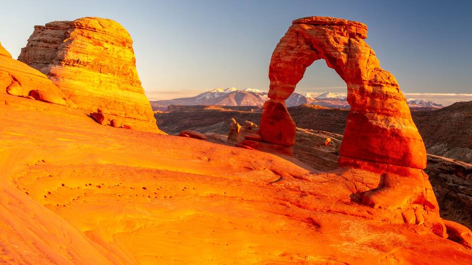 A desert landscape with prominent rock formations and a clear sky.