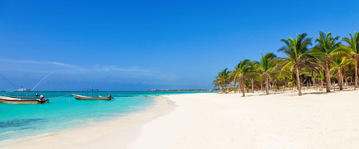 A beach with white sand, turquoise water, and palm trees.