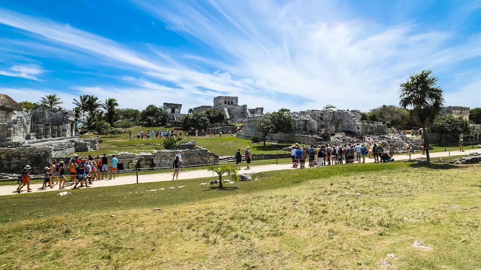 A historical site with ruins and a crowd of visitors.