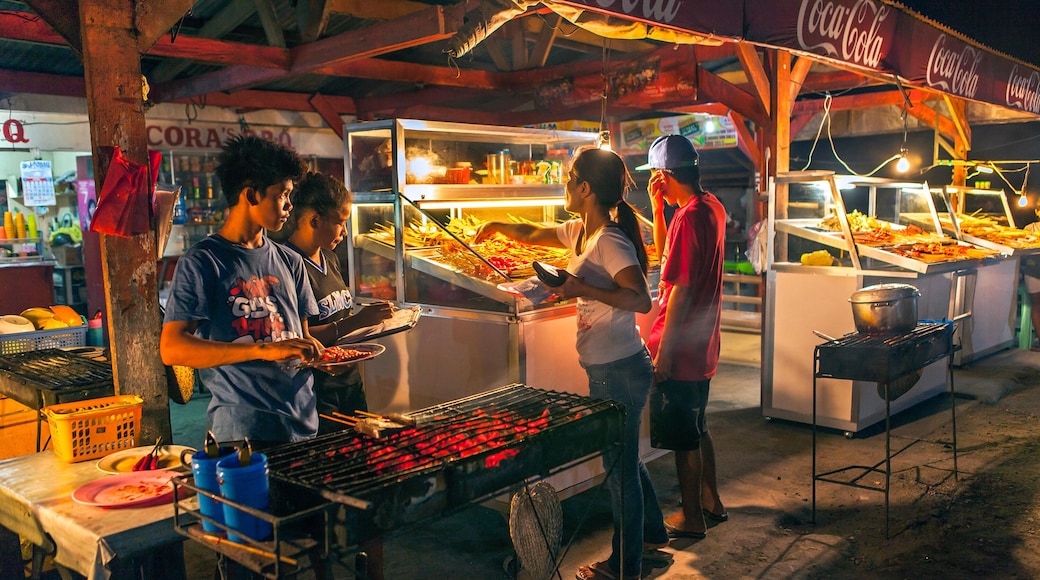 HF6B8G Customers at the night seaside barbecue stand buy skewers of variety meats and fish in Bogo City, Cebu Island, Philippines.