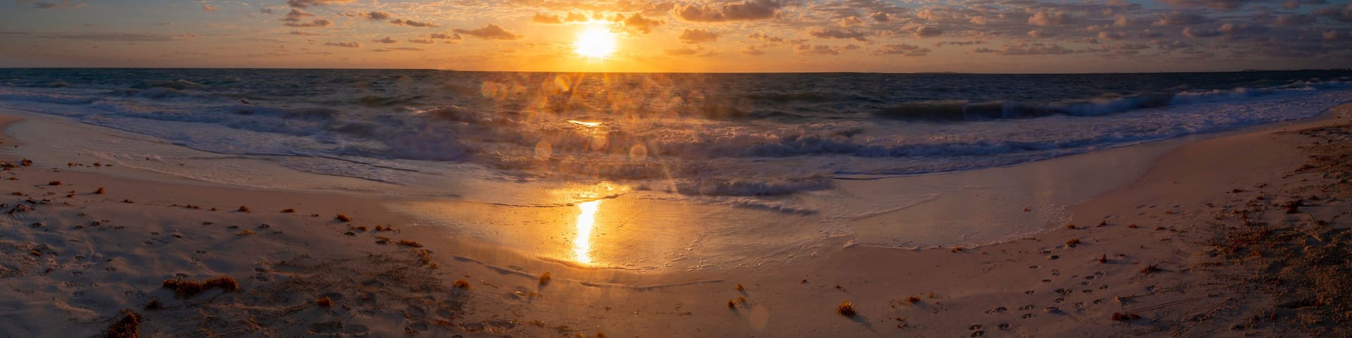 A beach at sunset with waves and a clear sky.