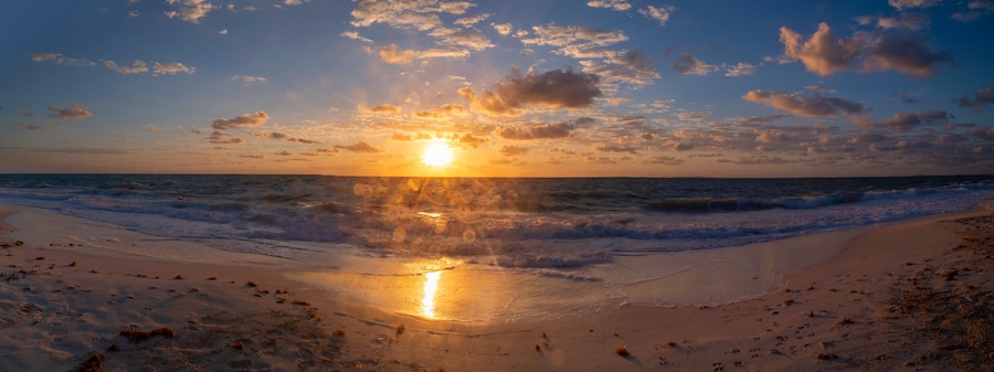 Una playa al atardecer con olas y un cielo despejado.