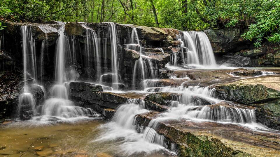 A multi-tiered waterfall surrounded by lush greenery.