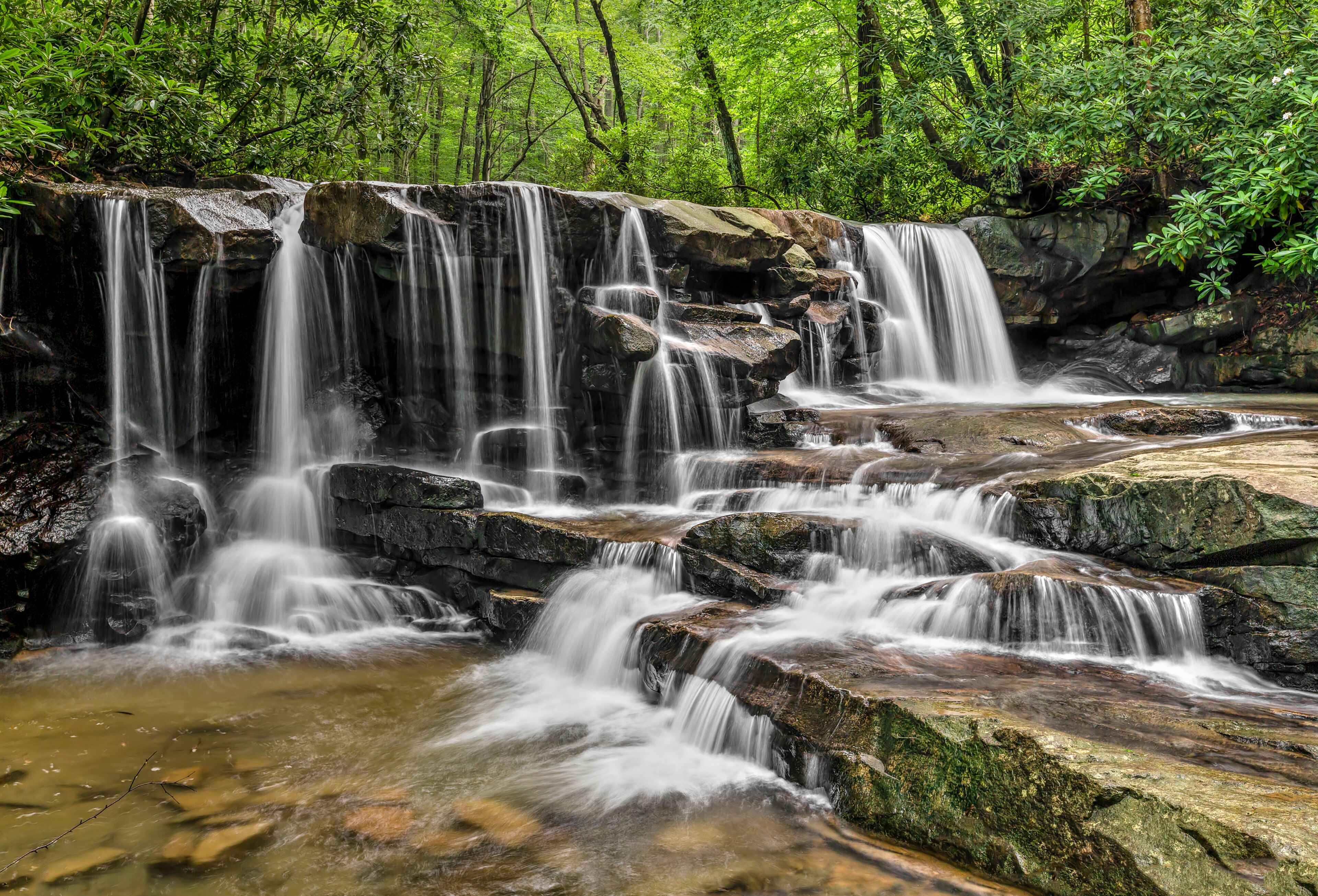 A multi-tiered waterfall surrounded by lush greenery.