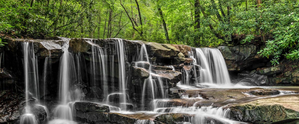 A multi-tiered waterfall surrounded by lush greenery.