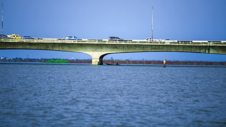 A concrete bridge over a body of water with vehicles crossing it.