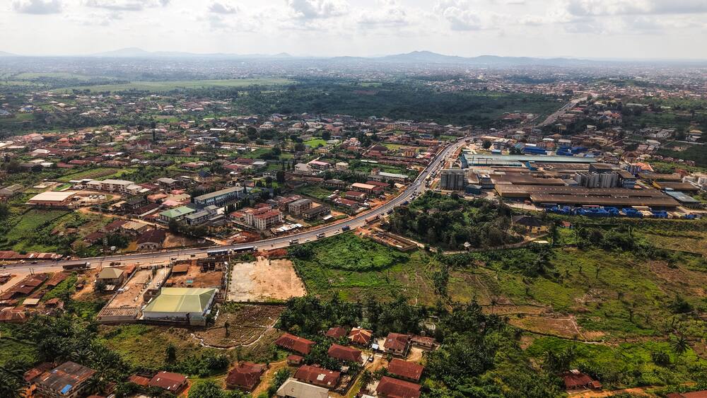 Aerial view of rooftops blending into the verdant landscape, a road cutting through the expanse of the city, Ilesa, Osun, Nigeria.