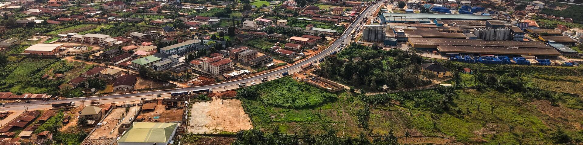 Aerial view of rooftops blending into the verdant landscape, a road cutting through the expanse of the city, Ilesa, Osun, Nigeria.