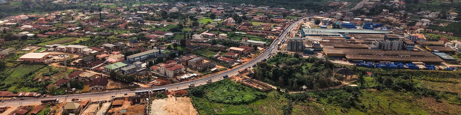 Aerial view of rooftops blending into the verdant landscape, a road cutting through the expanse of the city, Ilesa, Osun, Nigeria.