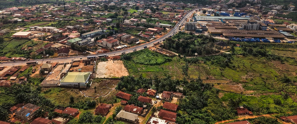 An aerial view of a city with a mix of residential and industrial areas, a prominent highway, and surrounding green landscapes.