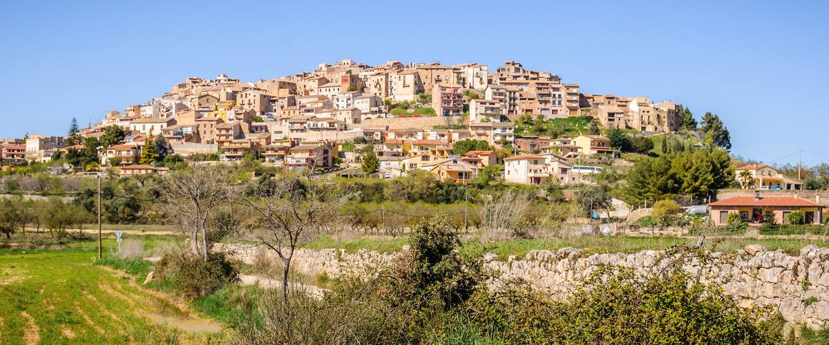 A hillside settlement with terraced houses and a stone wall in the foreground.