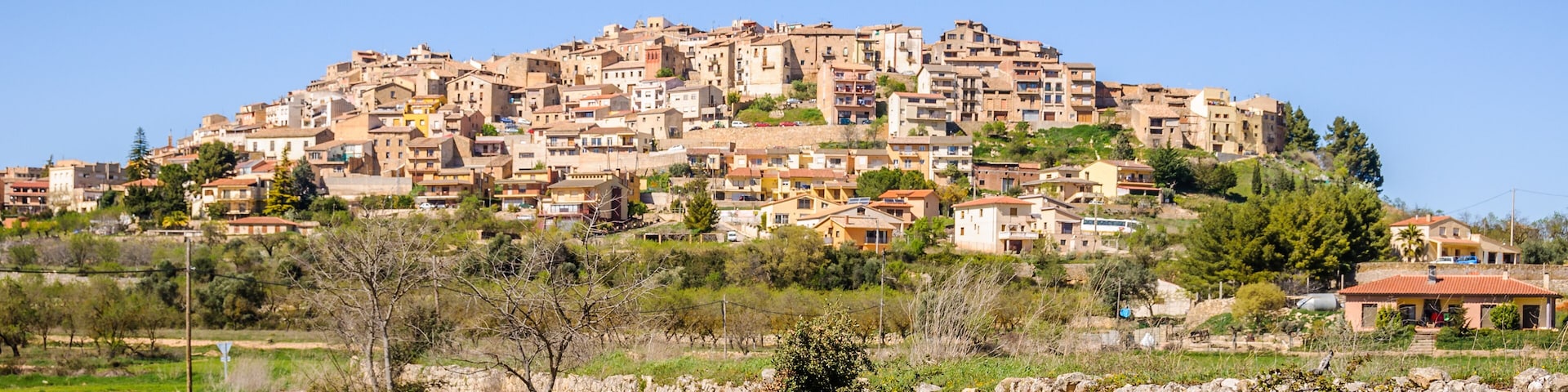 A hillside settlement with terraced houses and a stone wall in the foreground.