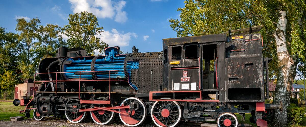 A blue and black steam locomotive with red wheels and a black caboose.