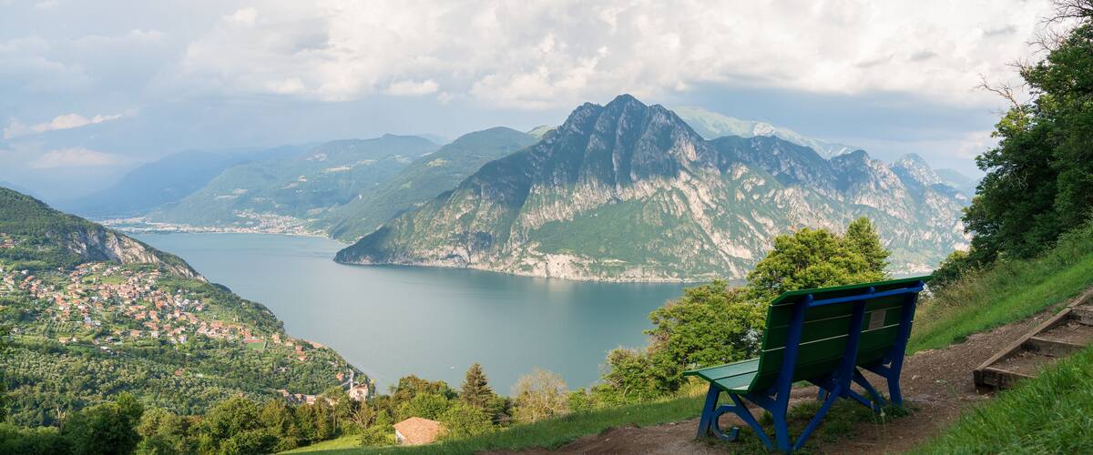 A bench overlooking a lake with mountains in the background.