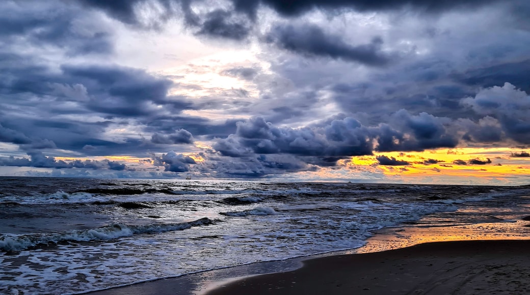 A beach with waves and a cloudy sky.