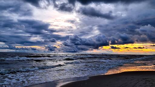 Ein Strand mit Wellen und einem bewölkten Himmel.
