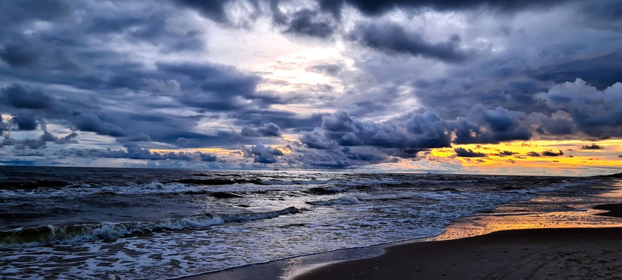 Uma praia com ondas e céu nublado.