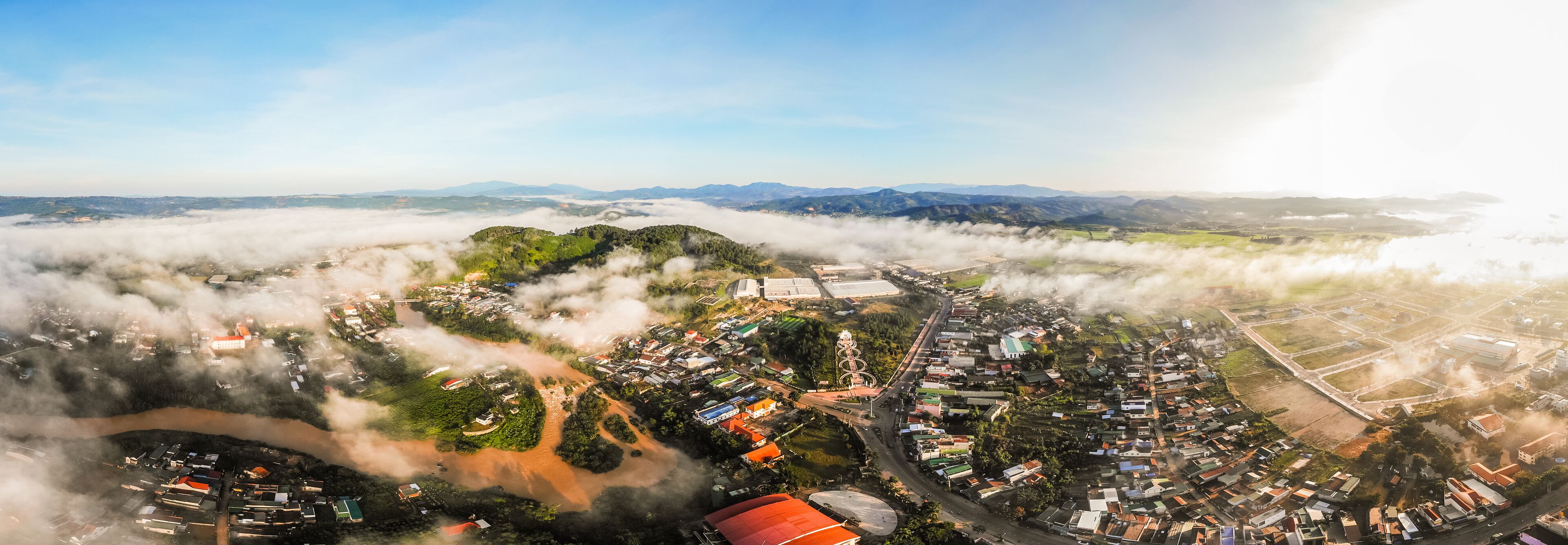 An aerial view of a town surrounded by mountains and enveloped in clouds.