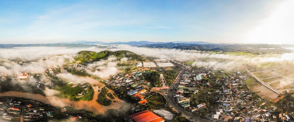 An aerial view of a town surrounded by mountains and enveloped in clouds.