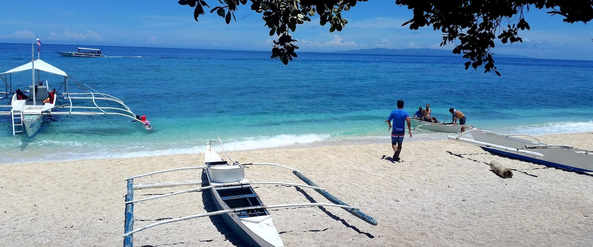 A beach with boats, a clear blue sky, and calm sea.