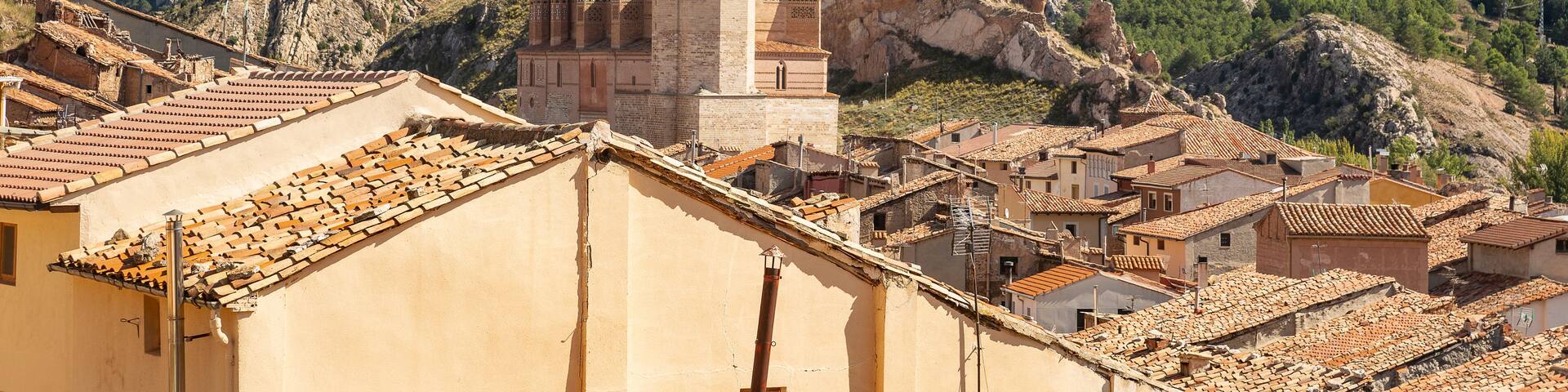 A mountainous landscape with a prominent church and terracotta-roofed buildings.