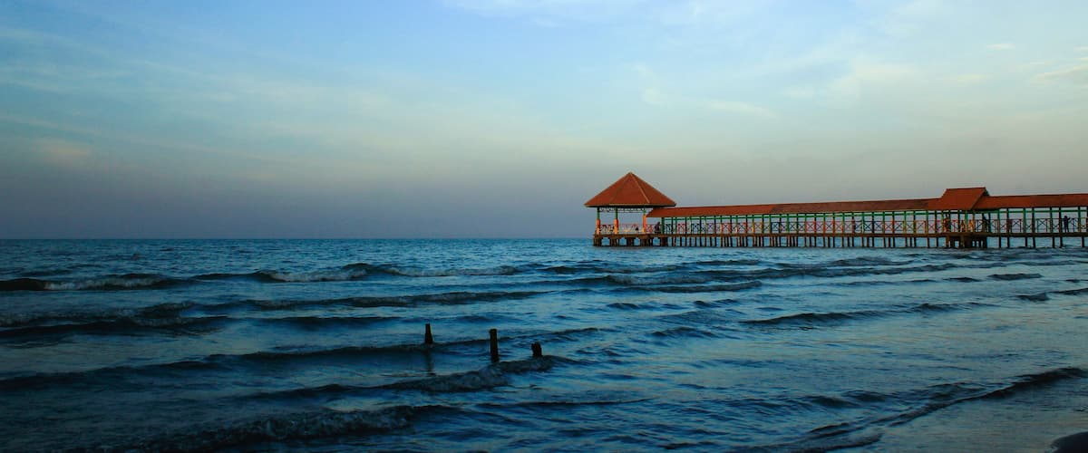 A pier extending into the ocean with a covered structure at the end.