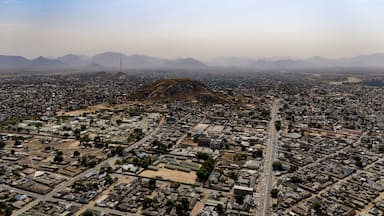 Aerial view of a sprawling cityscape nestled beneath a majestic mountain range, roads stretching like arteries through the urban landscape, Jalingo, Taraba, Nigeria.