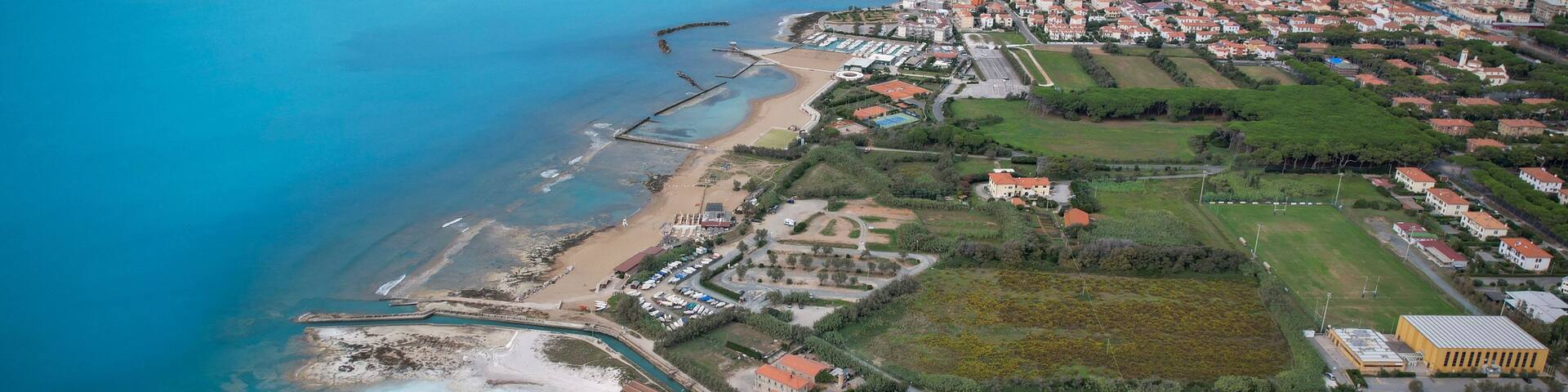 Aerial view of the coastline where the turquoise sea meets the white sandy beach and the green vegetation of the land, Rosignano Solvay, Tuscany, Italy.