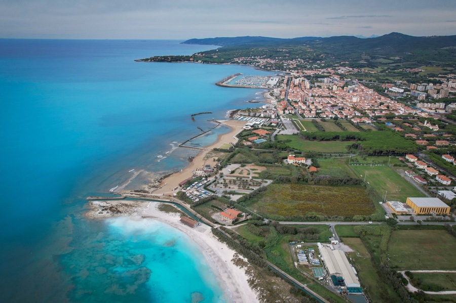 Aerial view of the coastline where the turquoise sea meets the white sandy beach and the green vegetation of the land, Rosignano Solvay, Tuscany, Italy.