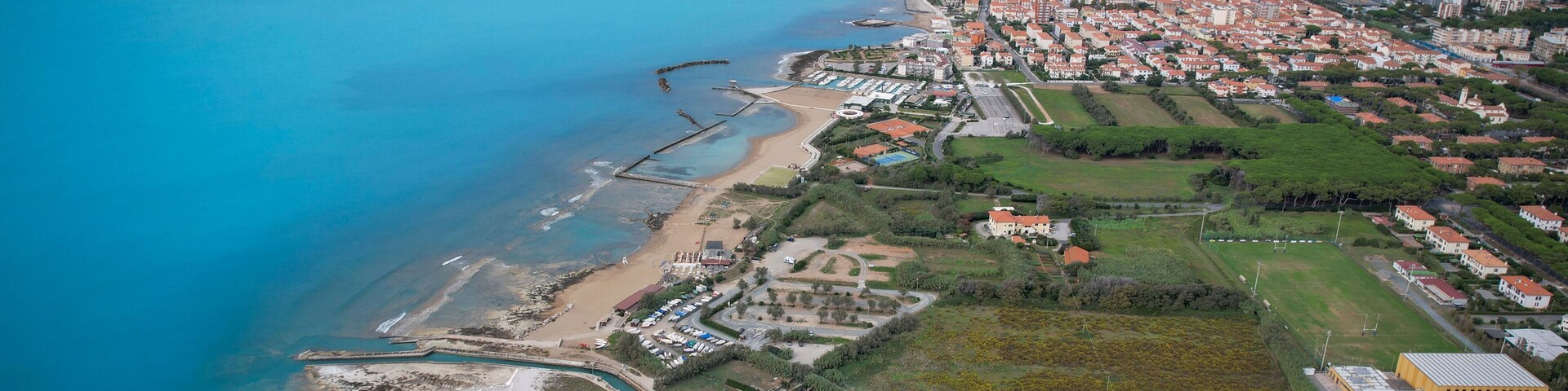 An aerial view of a coastal town with a beach, marina, and residential areas.