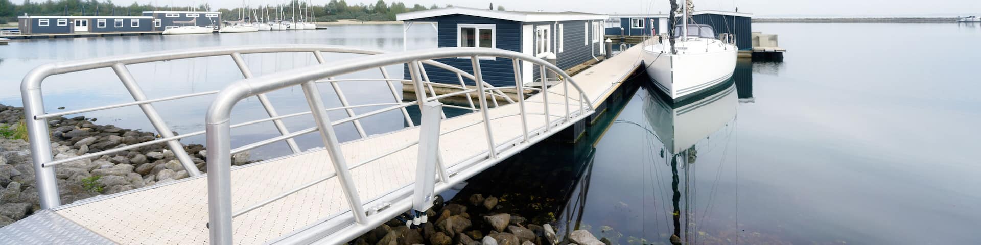 a jetty leads to vacation homes and a sailing boat on the Grevelingenmeer in the netherlands near by bruinisse