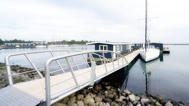 a jetty leads to vacation homes and a sailing boat on the Grevelingenmeer in the netherlands near by bruinisse