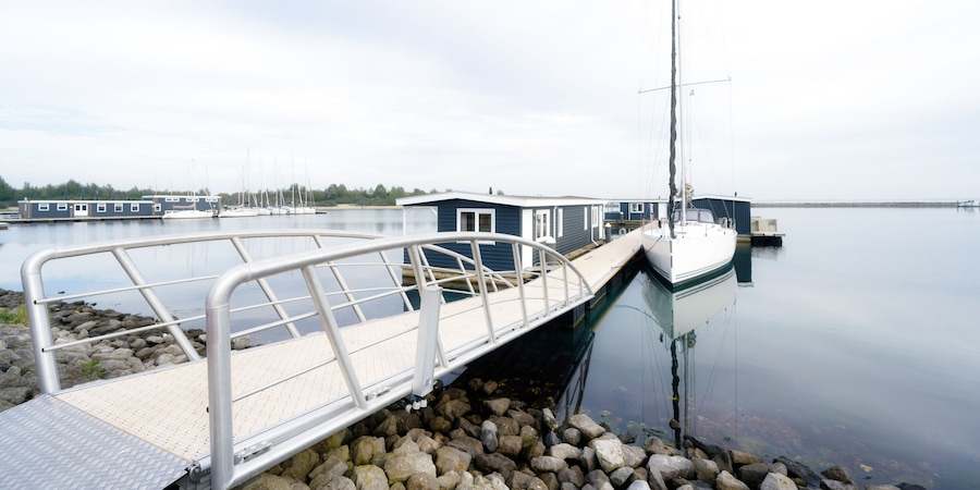 a jetty leads to vacation homes and a sailing boat on the Grevelingenmeer in the netherlands near by bruinisse