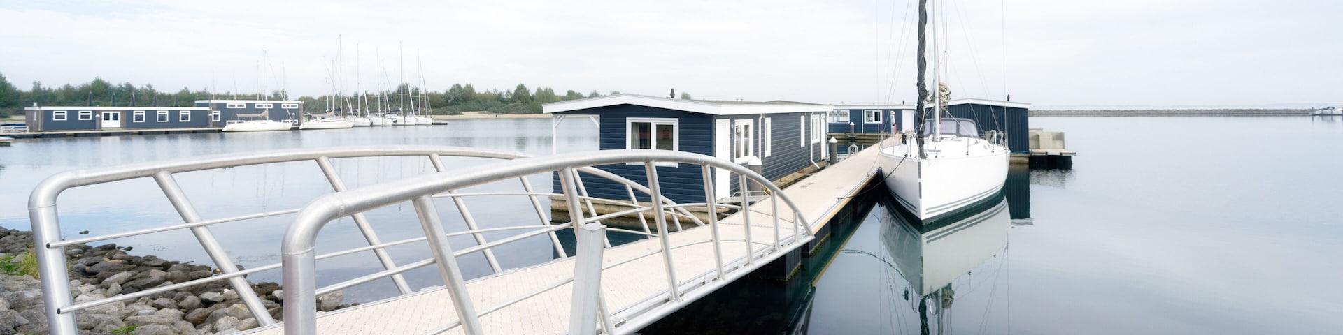 a jetty leads to vacation homes and a sailing boat on the Grevelingenmeer in the netherlands near by bruinisse