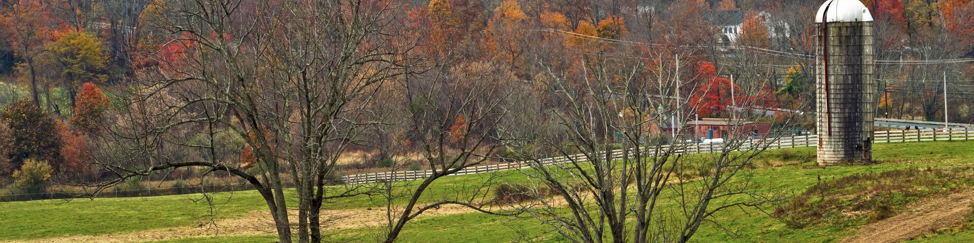 A rural landscape with a silo, a church, and autumn-colored trees.