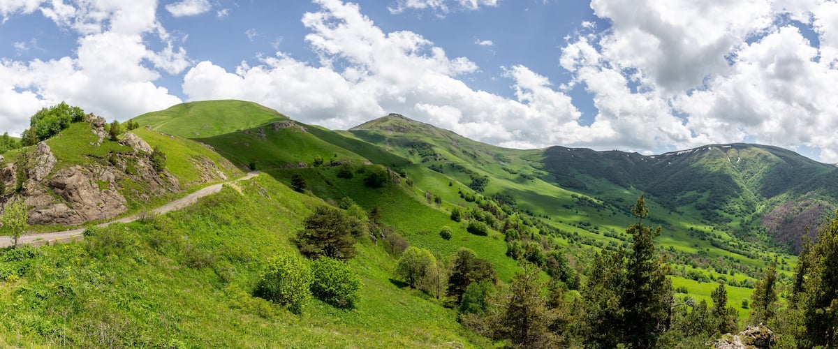 A lush green valley with rolling hills and a winding road.
