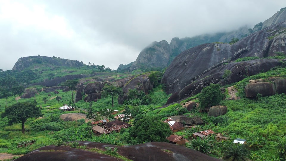A lush green landscape with large rock formations and scattered houses.