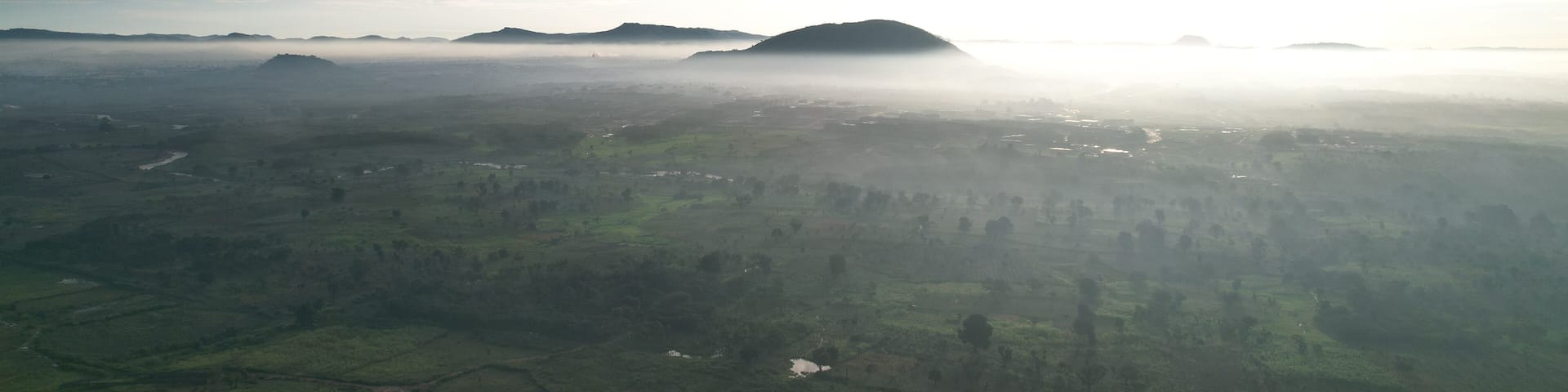 Aerial view of the landscape shrouded in a veil of early morning mist, with rolling hills rising above the fog, Akure, Ondo, Nigeria.