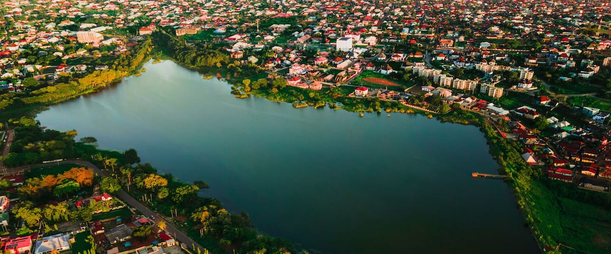 An aerial view of a lake surrounded by a densely populated residential area with various buildings and greenery.