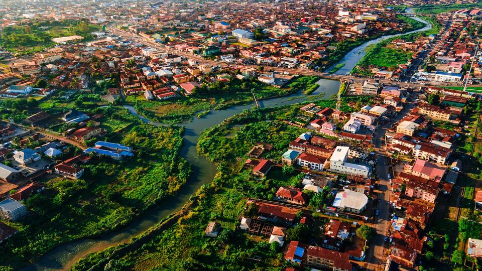An aerial view of a city with a river running through it, surrounded by greenery and buildings.