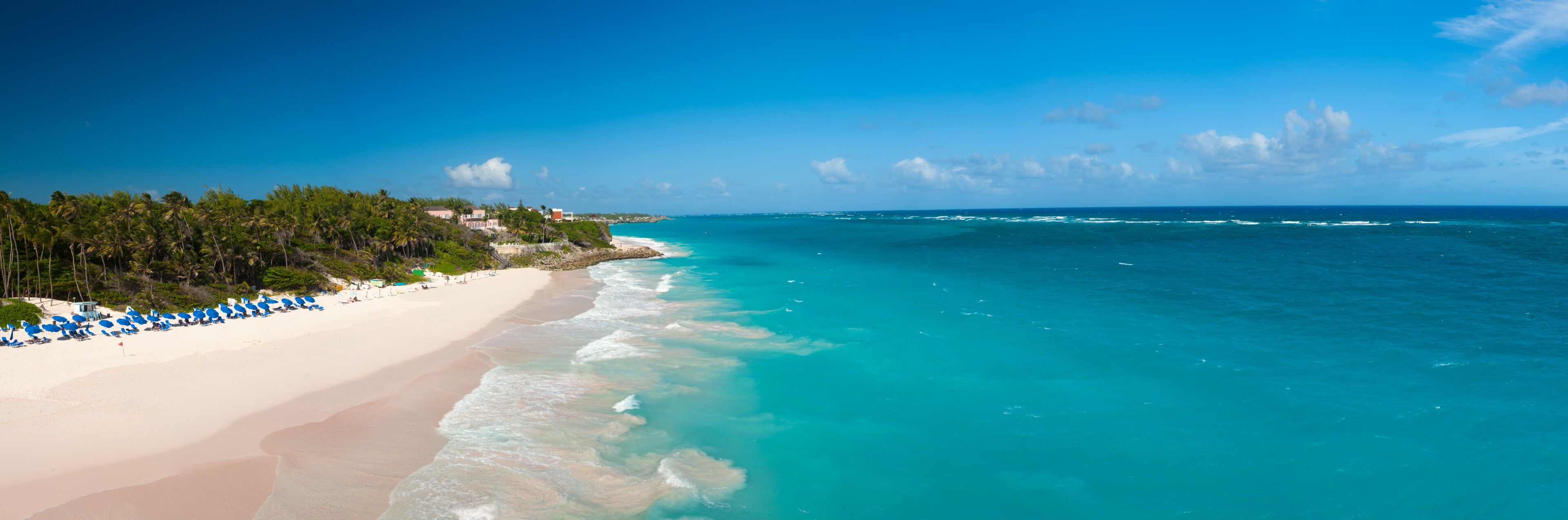 Una playa con aguas turquesas, arena blanca y palmeras.