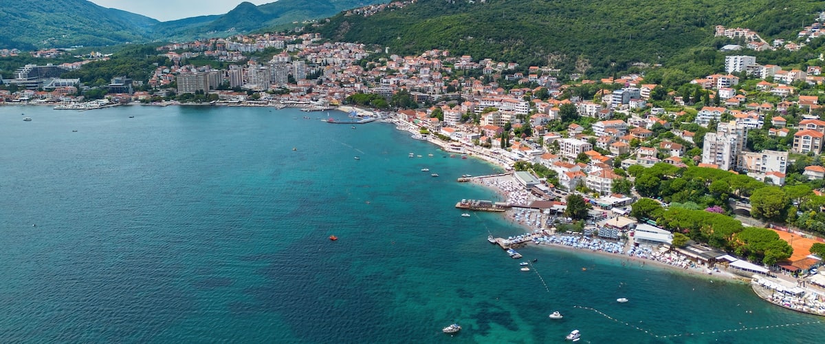 A coastal city with a bay, buildings, and mountains in the background.