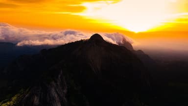 Aerial view of rocky outcrops rise majestically against a fiery sunset, their peaks kissing the clouds in a dance of light and shadow, Idanre, Ondo, Nigeria.